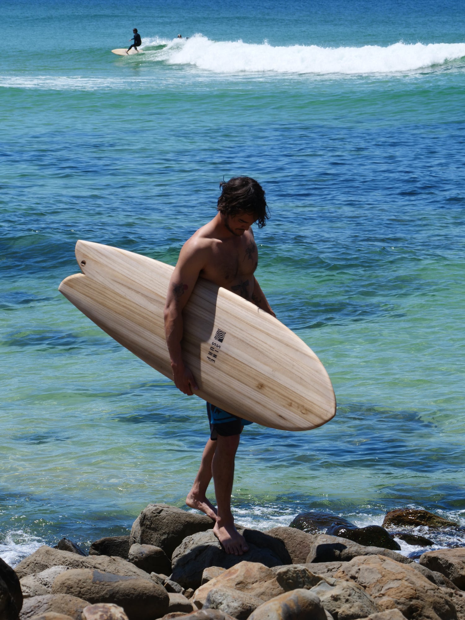 Surfer at boomerang beach holding a sustainable hollow wooden surfboard